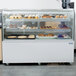 A bakery display case with pastries and cupcakes illuminated by an Avantco LED lamp.