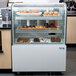 A refrigerated display case with pastries lit by an Avantco LED lamp.