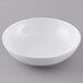 A Carlisle white melamine bowl on a gray surface.