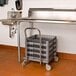 A Noble Products gray dish rack and glass rack dolly with a 31" handle on a metal cart in a kitchen.