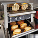 A piece of bread being toasted in a Vollrath JT2000 conveyor toaster with a rack.