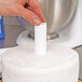 A person using Wilton plastic cake pillars to cut a white cake.