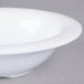 A close-up of a white Carlisle melamine fruit bowl with a rim.