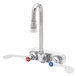 A T&S chrome wall mount faucet with swivel gooseneck nozzle and wrist handles.