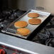 A Vigor portable steel griddle with pancakes cooking on a stove.