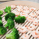 A Town bamboo steamer holding a plate of broccoli and shrimp on a wooden surface.