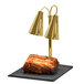A Hanson brass carving station with dual heat lamps over a piece of meat on a black granite base.