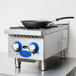A Globe stainless steel countertop gas hot plate with a pan on it.