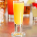 A Libbey cordial glass filled with orange juice on a table.