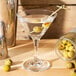A Libbey martini glass filled with liquid and olives.