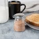 A Tablecraft glass jar with a metal clip-top lid filled with brown powder on a table with toast and a glass of milk.