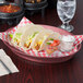 HS Inc. raspberry oval deli server filled with a plate of tacos and red salsa on a table in a Mexican restaurant.