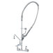 A chrome T&S wall mounted pre-rinse faucet with a curved silver hose.