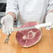 A person in white gloves using a Dexter-Russell narrow duo-edge meat slicer to cut a piece of meat.