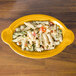 A Fiesta Daffodil oval china baker filled with pasta and vegetables.