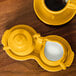 A yellow Fiesta sugar and creamer tray set with a creamer and a cup of coffee.