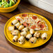 A Fiesta China pizza tray with pizza and bread rolls on it.