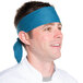 A man wearing a teal chef neckerchief on his head.