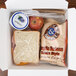 A white Fold-Pak Bio-Pak take-out box filled with a sandwich, apple, and bread.