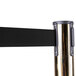 A brass Aarco crowd control stanchion with dual black retractable belts.