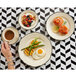 A hand holding a cup of coffee next to a Homer Laughlin black scalloped china plate of food with a fried egg and asparagus.