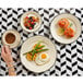 A woman's hand holding a cup of coffee on a Homer Laughlin Styleline Black china plate with food including a fried egg and asparagus.
