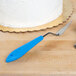 An Ateco offset baking spatula with a white plastic handle cutting a cake.