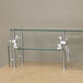 A glass food shield for a counter with metal legs and a glass top.