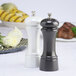 A Chef Specialties gunmetal pepper mill and pearl metallic salt mill on a table.