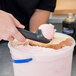 A hand using a Zeroll Zerolon ice cream scoop to scoop pink ice cream.