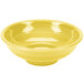 A yellow pedestal serving bowl with a white rim.