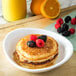 A stack of pancakes with berries on top on a white Carlisle melamine pasta plate.
