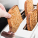 A person holding a slice of bread above a Waring commercial toaster.
