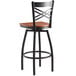 A Lancaster Table & Seating black cross back swivel bar stool with cherry wood seat.