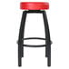 A black swivel bar stool with a red round vinyl seat.