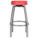 A close-up of a Lancaster Table & Seating clear coat metal swivel bar stool with a red vinyl seat.
