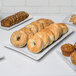 A 10 Strawberry Street blue speckled rectangular porcelain platter holding pastries, muffins, and bagels.