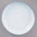 A white porcelain plate with blue speckles on it.