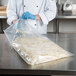 A chef using a VacPak-It chamber vacuum packaging pouch to store shredded cheese.
