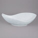 A white porcelain canoe bowl with blue speckled design.