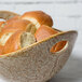 A 10 Strawberry Street porcelain bowl with cut-out handles filled with bread rolls.