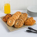 A 10 Strawberry Street Tiger Eye square porcelain platter with bagels, pastries, and orange juice on it.