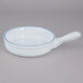 A white porcelain casserole bowl with a blue rim and handle.