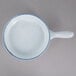 A white porcelain casserole bowl with a blue interior and a handle.