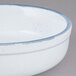 A white porcelain casserole bowl with a blue rim and a handle.