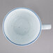 A white porcelain cup with blue specks on it.