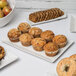 A rectangular porcelain platter with muffins and cookies on a table.