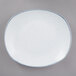 A white porcelain rectangular dinner plate with a blue speckled rim.