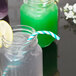 A glass jar with a teal paper straw in it and a lemon slice.