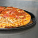A Solut black coated paperboard tray with a pepperoni and cheese pizza cooking in it.